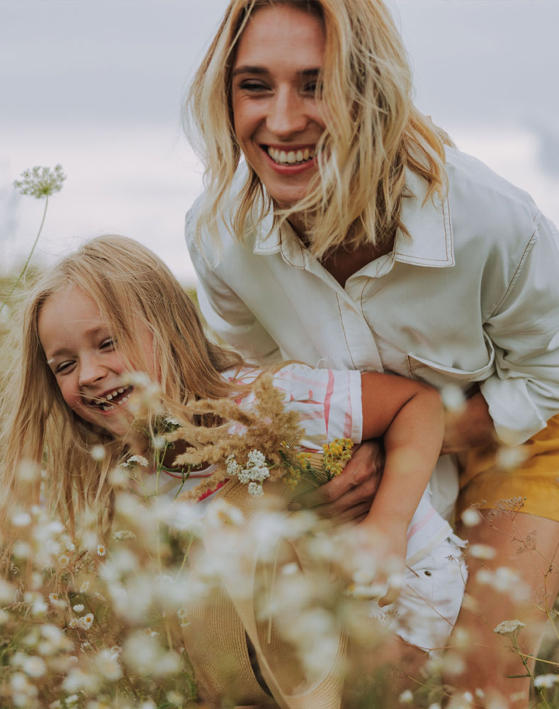 A mother and daughter laughing together in a field of wildflowers